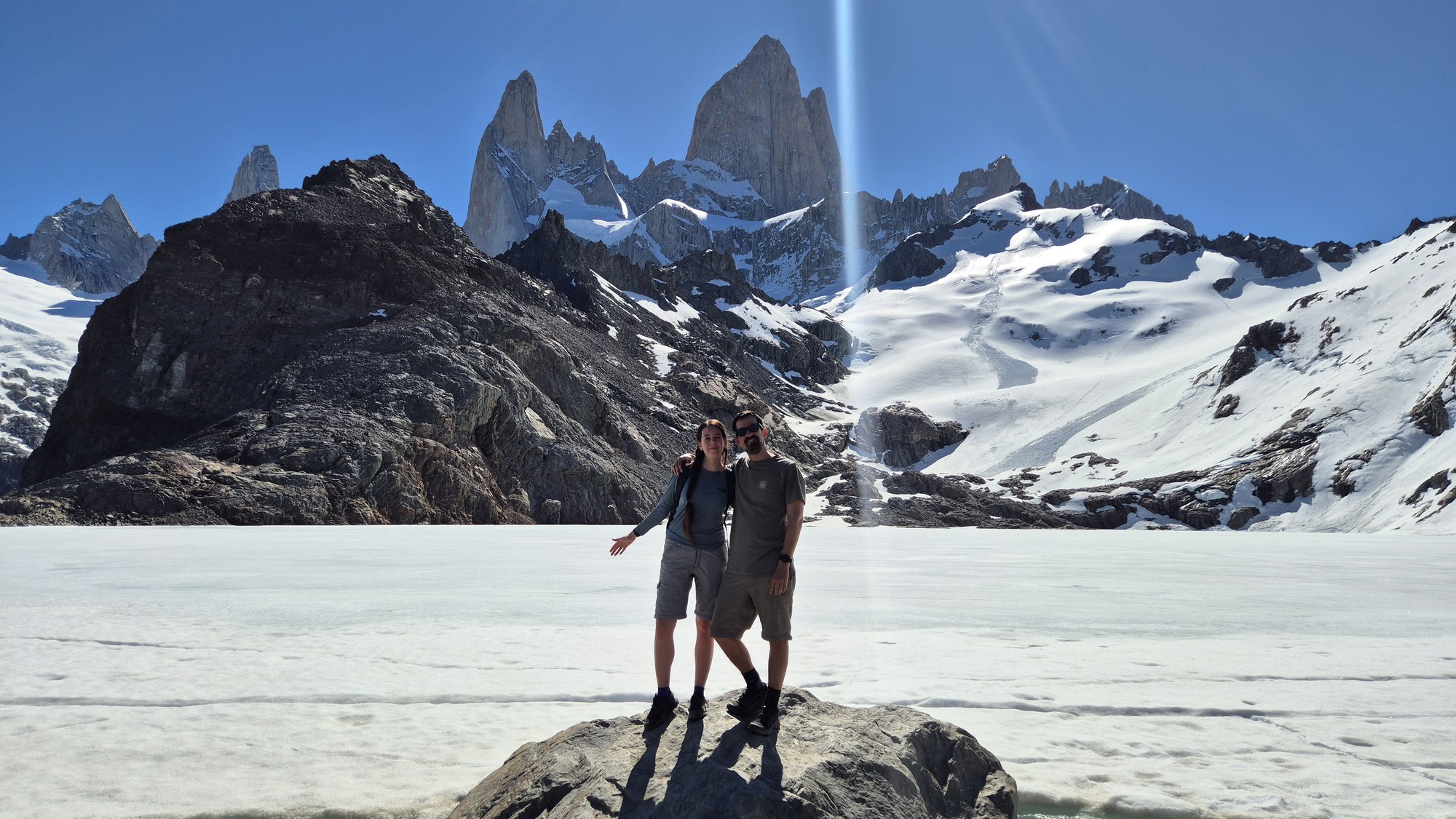 Clari y Fede juntos frente a una laguna y montañas nevadas